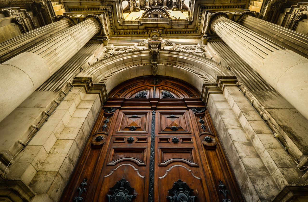 Close-up view of a grand gothic cathedral entrance with detailed columns and a historic wooden door.